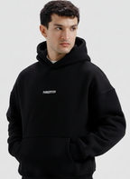 Man wearing a black hoodie with a brand logo on a light gray background