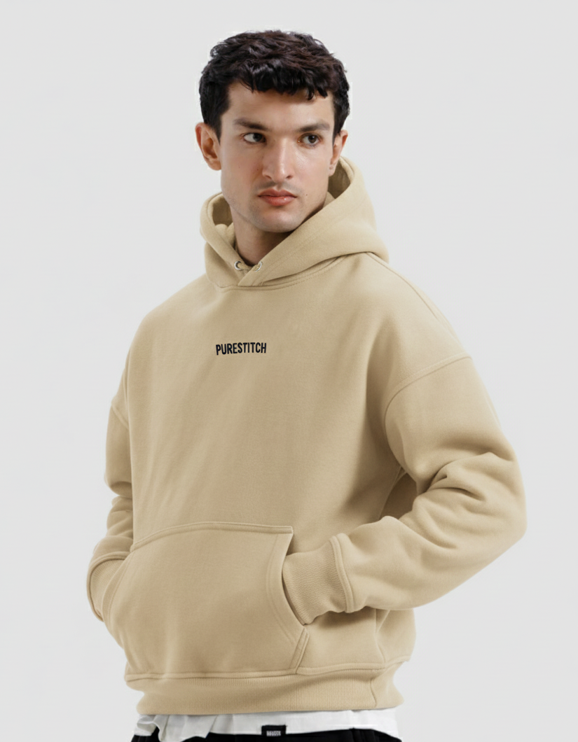 Man wearing a beige hoodie with 'PURESTITCH' branding on a white background