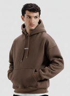 Man wearing a brown hoodie on a light gray background