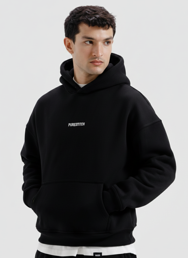 Man wearing a black hoodie with a brand logo on a light gray background